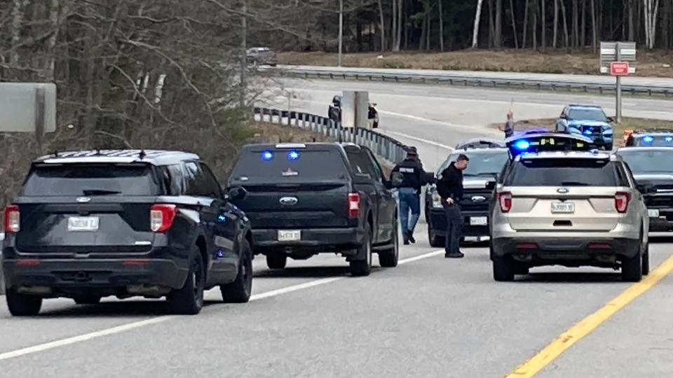 Members of law enforcement approach vehicles at a scene where people were injured in a shooting on Interstate 295 in Yarmouth, Maine, Tuesday, April 18, 2023. Gunfire that erupted on the busy highway in Maine is linked to a second crime scene where people have been found dead in a home about 25 miles away in the town of Bowdoin, Maine, state police said Tuesday. (AP Photo/Patrick Whittle)