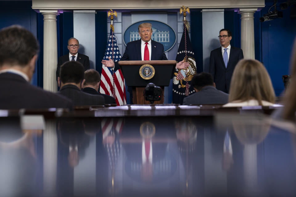 President Donald Trump speaks during a news briefing at the White House, Thursday, July 2, 2020, in Washington, as White House chief economic adviser Larry Kudlow, left, and Treasury Secretary Steven Mnuchin, look on. (AP Photo/Evan Vucci)