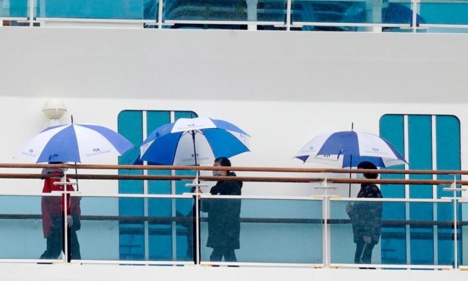 Passengers wearing masks walk on a deck of the Diamond Princess cruise ship docked in Yokohama.