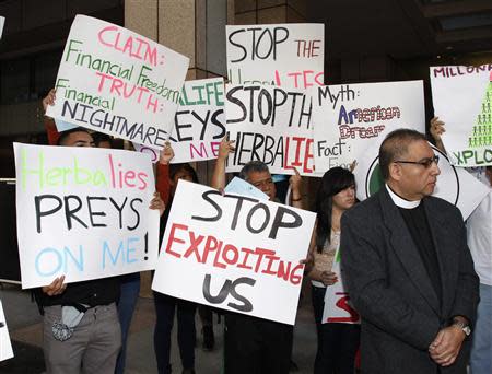 Demonstrators protesting against Herbalife, a nutrition and supplements company, hold signs outside the Ronald Reagan State Office building in Los Angeles, California October 18, 2013. According to the protestors, they are seeking action against Herbalife's business practices. REUTERS/Fred Prouser