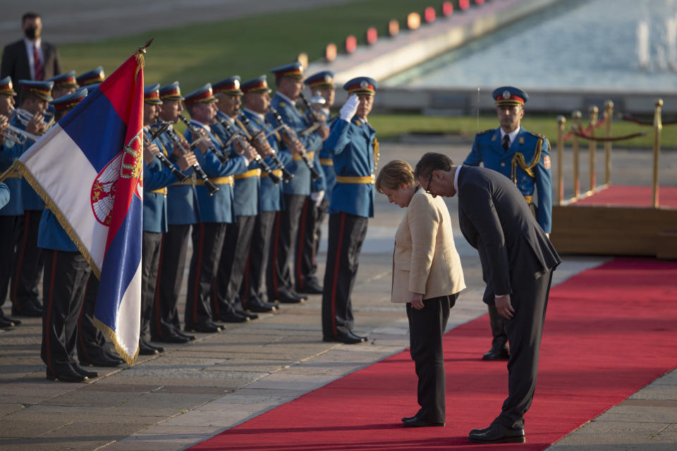 German Chancellor Angela Merkel, center, bows to the Serbian flag while being accompanied by Serbia's president Aleksandar Vucic, front right, in Belgrade, Serbia, Monday, Sept. 13, 2021. Merkel is on a farewell tour of the Western Balkans, as she announced in 2018 that she wouldn't seek a fifth term as Germany's Chancellor. (AP Photo/Marko Drobnjakovic)