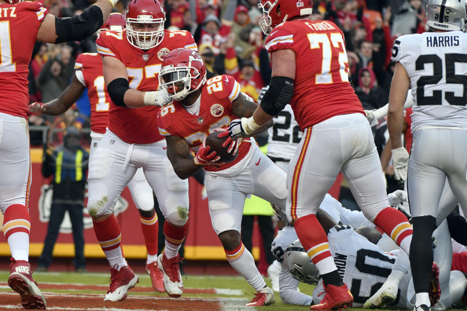 Kansas City Chiefs running back Damien Williams (26) scores a touchdown between offensive guard Andrew Wylie (77) and offensive tackle Eric Fisher (72) and past Oakland Raiders linebacker Nicholas Morrow (50) during the first half of an NFL football game in Kansas City, Mo., Sunday, Dec. 30, 2018. (AP Photo/Ed Zurga)