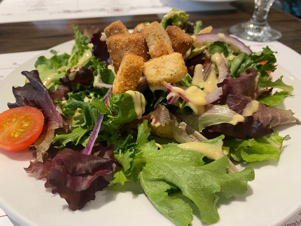 Salad with greens, tomatoes, and croutons on white plate at le creperie de paris at epcot