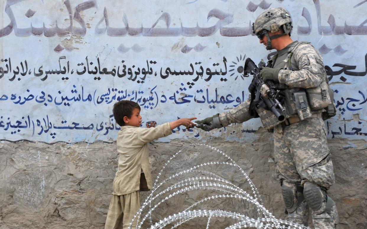 A US soldier from 4th Infantry Division 4 Brigade Alpha Company presents a gift to an Afghan child during a patrol at Khogiani in Langarhar  - KIM JAE-HWAN /AFP