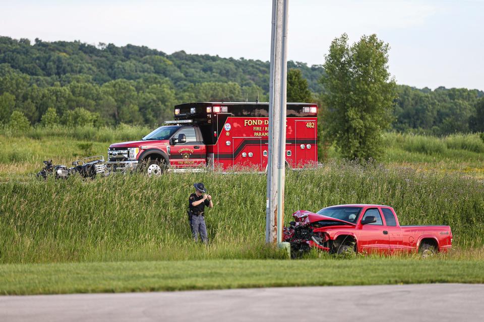 A Wisconsin State Patrol officer takes photos of a crash scene involving a red pickup truck and a motorcycle July 3, 2020, on Winnebago Drive near State Highway 151 northeast of Fond du Lac.