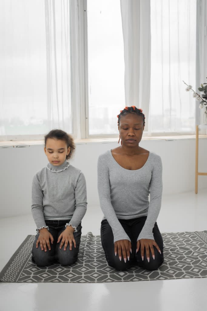 Black mother and daughter meditating together