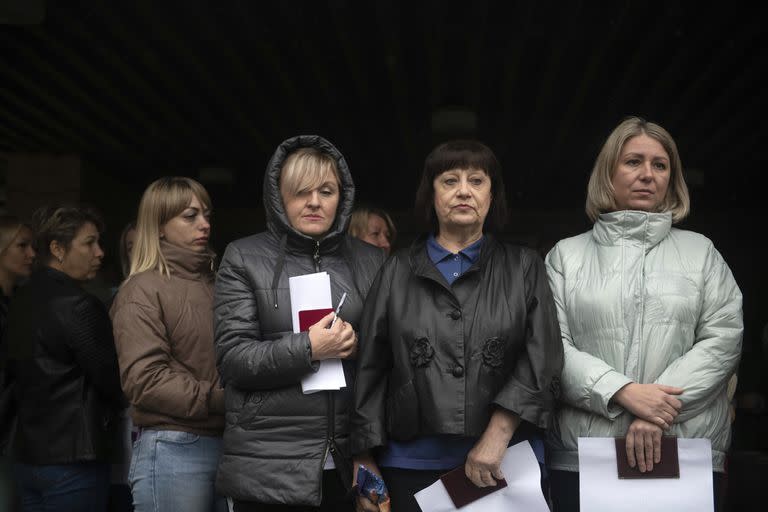 La gente espera para asistir a la votación en un referéndum frente a un colegio electoral móvil en Lugansk, este de Ucrania, el viernes 23 de septiembre de 2022.