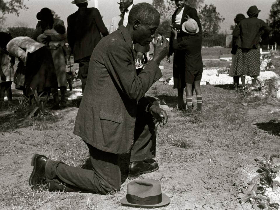 A man prays over the grave of a relative in a cemetery on All Saints' Day in New Roads, Louisiana, 1938.