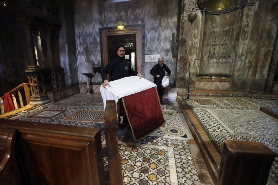 Workers clean up after high waters flooded the interior of St. Mark's Basilica, in Venice, Wednesday, Nov. 13, 2019. The high-water mark hit 187 centimeters (74 inches) late Tuesday, Nov. 12, 2019, meaning more than 85% of the city was flooded. The highest level ever recorded was 194 centimeters (76 inches) during infamous flooding in 1966. (AP Photo/Luca Bruno)