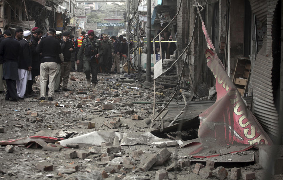 Pakistani police officers examine the site of bomb blast in Peshawar, Pakistan, Saturday, Jan. 5, 2019. Pakistani police say a car bomb exploded in a Peshawar neighborhood wounding three people and damaging several shops. (AP Photo/Mohammad Sajjad)