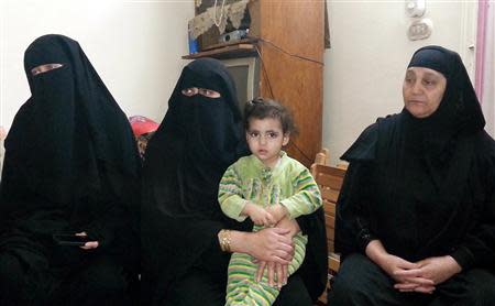 The wife (L) and other family members of Fahmy Abdel Raouf, who was killed with his 13-year-old son in a gun battle with security forces, sit in their flat in the Matariya area of Cairo April 13, 2014. Picture taken April 13. REUTERS/Stringer