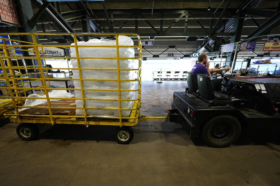 A tug driver pulls a trailer of bags of ice for use in concession stands on the main concourse of Coors Field before the Colorado Rockies host the Pittsburgh Pirates in a baseball game Sunday, June 16, 2024, in Denver. (AP Photo/David Zalubowski)