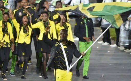 Jamaica's flag bearer Usain Bolt holds the national flag as he leads the contingent in the athletes parade during the opening ceremony of the London 2012 Olympic Games at the Olympic Stadium