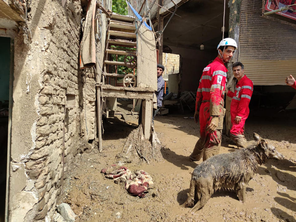 In this photo provided by the Iranian Red Crescent Society, members of a rescue team work at the scene of a flash flood in the northwestern part of Tehran, Iran, Thursday, July 28, 2022. Heavy rains in the early hours of Thursday caused flash floods and then landslides and caused damage to Imamzadeh Davood, a religious shrine in the city. (Iranian Red Crescent Society via AP)