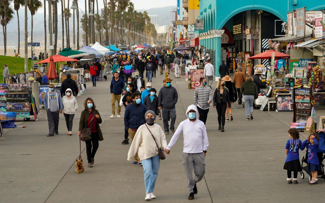 People stroll on the Venice Beach Boardwalk. In Los Angeles County, the nation's most populous, county estimates show that about 1 in 95 people are contagious with the coronavirus - AP