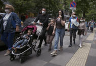 Turkish children under 14 with their parents wearing face masks for protection against the coronavirus, walk in popular Tunali Hilmi Street, in Ankara, Turkey, Wednesday, May 27, 2020. Children were allowed to go out between 12:00-15:00 local time for the third time. AP Photo/Burhan Ozbilici)