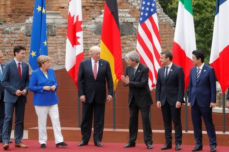FILE PHOTO: From L-R, European Council President Donald Tusk, Canadian Prime Minister Justin Trudeau, German Chancellor Angela Merkel, U.S. President Donald Trump, Italian Prime Minister Paolo Gentiloni, French President Emmanuel Macron, Japanese Prime Minister Shinzo Abe react during a family photo during the G7 Summit in Taormina, Sicily, Italy, May 26, 2017. REUTERS/Philippe Wojazer/File Photo