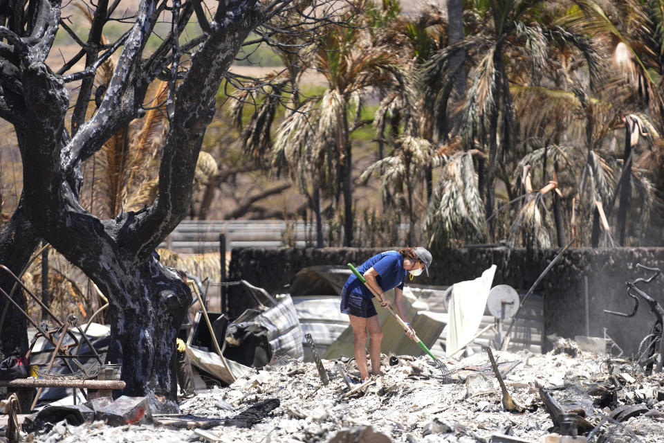 FILE - A woman digs through rubble of a home destroyed by a wildfire on Aug. 11, 2023, in Lahaina, Hawaii. With a housing crisis that has priced out many Native Hawaiians as well as families that have been there for decades, concerns are rising that Maui could become the latest example of “climate gentrification,” when it becomes harder for local people to afford housing in safer areas after a climate-amped disaster. (AP Photo/Rick Bowmer, File)