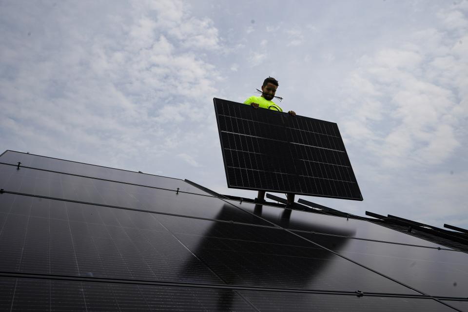 Nicholas Hartnett, owner of Pure Power Solar, holds a panel as his company installs a solar array on the roof of a home in Frankfort, Ky., Monday, July 17, 2023. Since passage of the Inflation Reduction Act, it has boosted the U.S. transition to renewable energy, accelerated green domestic manufacturing, and made it more affordable for consumers to make climate-friendly purchases, such as installing solar panels on their roofs. (AP Photo/Michael Conroy)