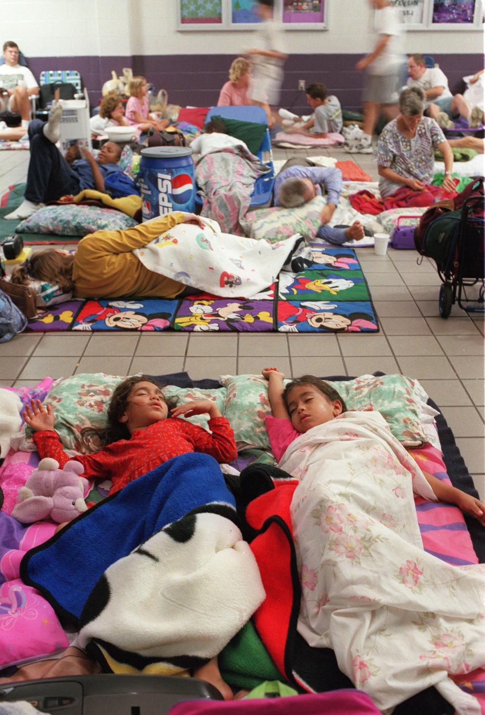 Josephine Kavanagh, left, 5, and her sister Jessica, 7, sleep at the overcrowded hurricane shelter at Landmark Middle School on Kernan Boulevard during Hurricane Floyd in 1999. Their father, Joseph, was assigned to the USS Hue City, which was deployed to ride out Hurricane Floyd.