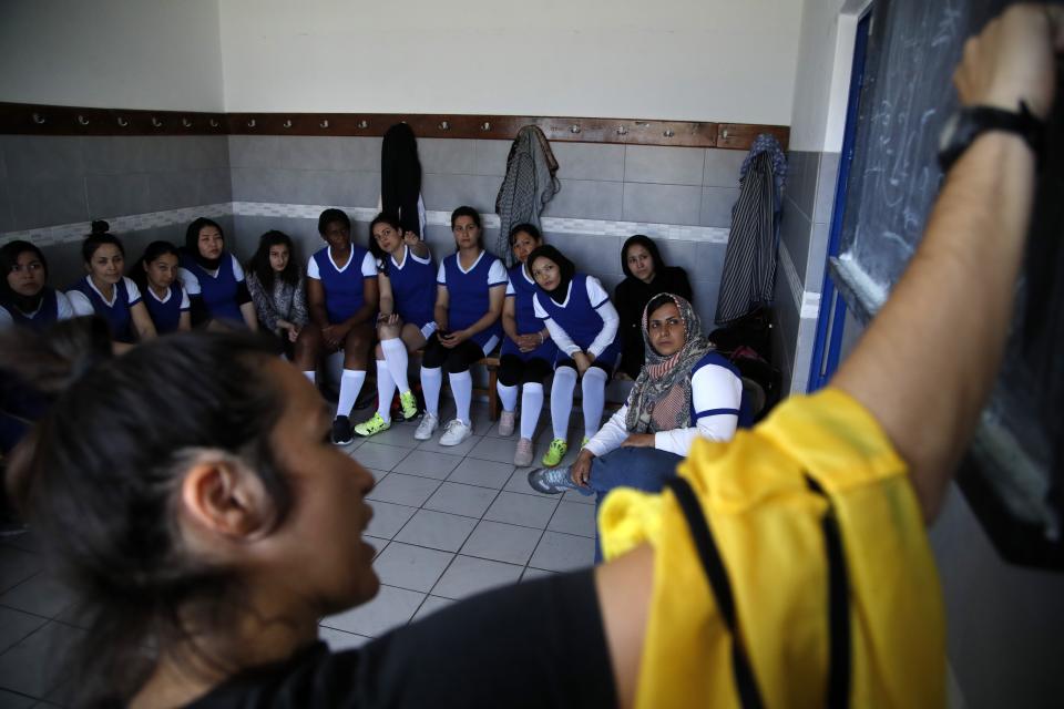 In this Thursday, May 2, 2019 photo, coach of Hestia FC Women's Refugee Soccer team Mary Gavala gives instructions to her players before a friendly game in Athens. Many of the players at Hestia FC weren't allowed to play or even watch soccer matches in their home countries. Hestia FC was set up by the Olympic Truce Centre, a non-government organization created in 2000 by the International Olympic Committee and Greek Foreign Ministry. (AP Photo/Thanassis Stavrakis)