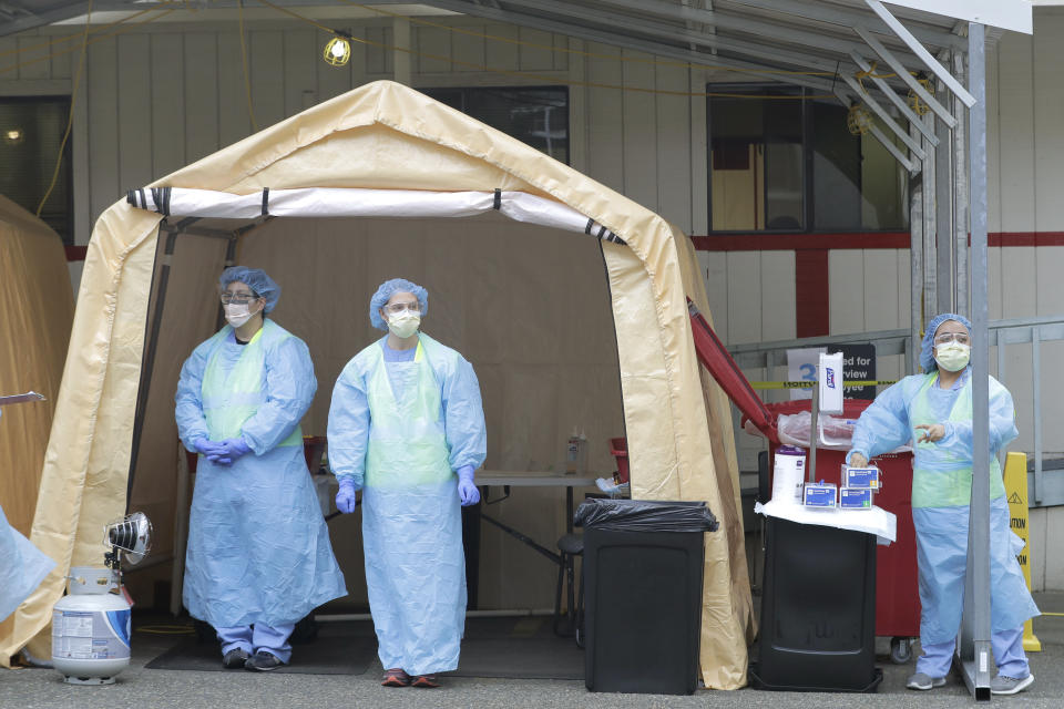 Nurses wait for cars at a drive-up coronavirus testing station at Harborview Medical Center hospital, Thursday, April 2, 2020, in Seattle. The facility saw a steady stream of employees and patients with symptoms Thursday as testing, which has been going on for several weeks, continued as part of efforts to slow the spread of the new coronavirus. (AP Photo/Ted S. Warren)