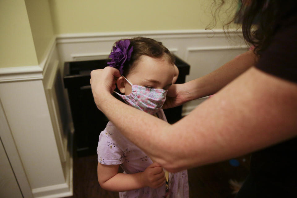 FILE - In this Aug. 3, 2020, file photo, Rachel Adamus, right, helps her daughter Neva, 5, put on her mask before her first day of kindergarten in Dallas, Ga. As schools reopen around the country, their ability to quickly identify and contain coronavirus outbreaks before they get out of hand is about to be put to the test. (AP Photo/Brynn Anderson, File)