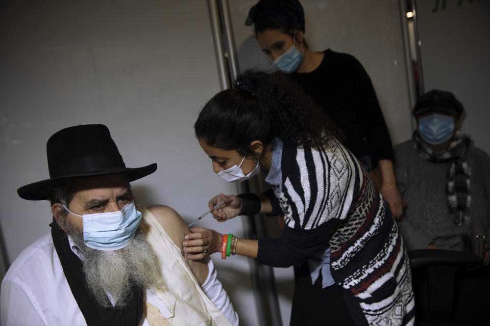 A man receives a coronavirus vaccine from medical staff at a COVID-19 vaccination center in Jerusalem, Monday, Jan. 4, 2021. (AP Photo/Oded Balilty)