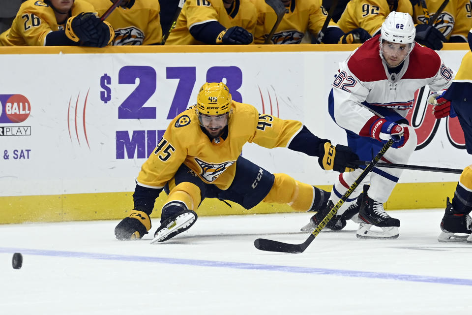 Montreal Canadiens left wing Artturi Lehkonen (62) passes the puck away from Nashville Predators defenseman Alexandre Carrier (45) during the first period of an NHL hockey game Saturday, Dec. 4, 2021, in Nashville, Tenn. (AP Photo/Mark Zaleski)