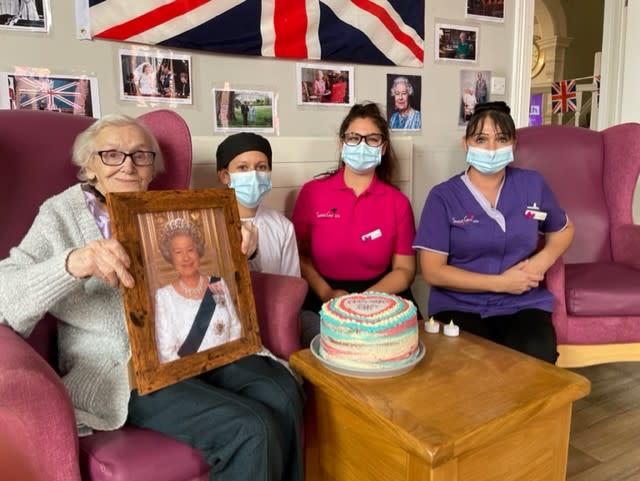 Resident Phyllis Padgham and staff at St Cecilia’s Nursing Home in Scarborough pictured with a photograph of the Queen and a red, white and blue layered cake. (St Cecilia’s care home/PA)