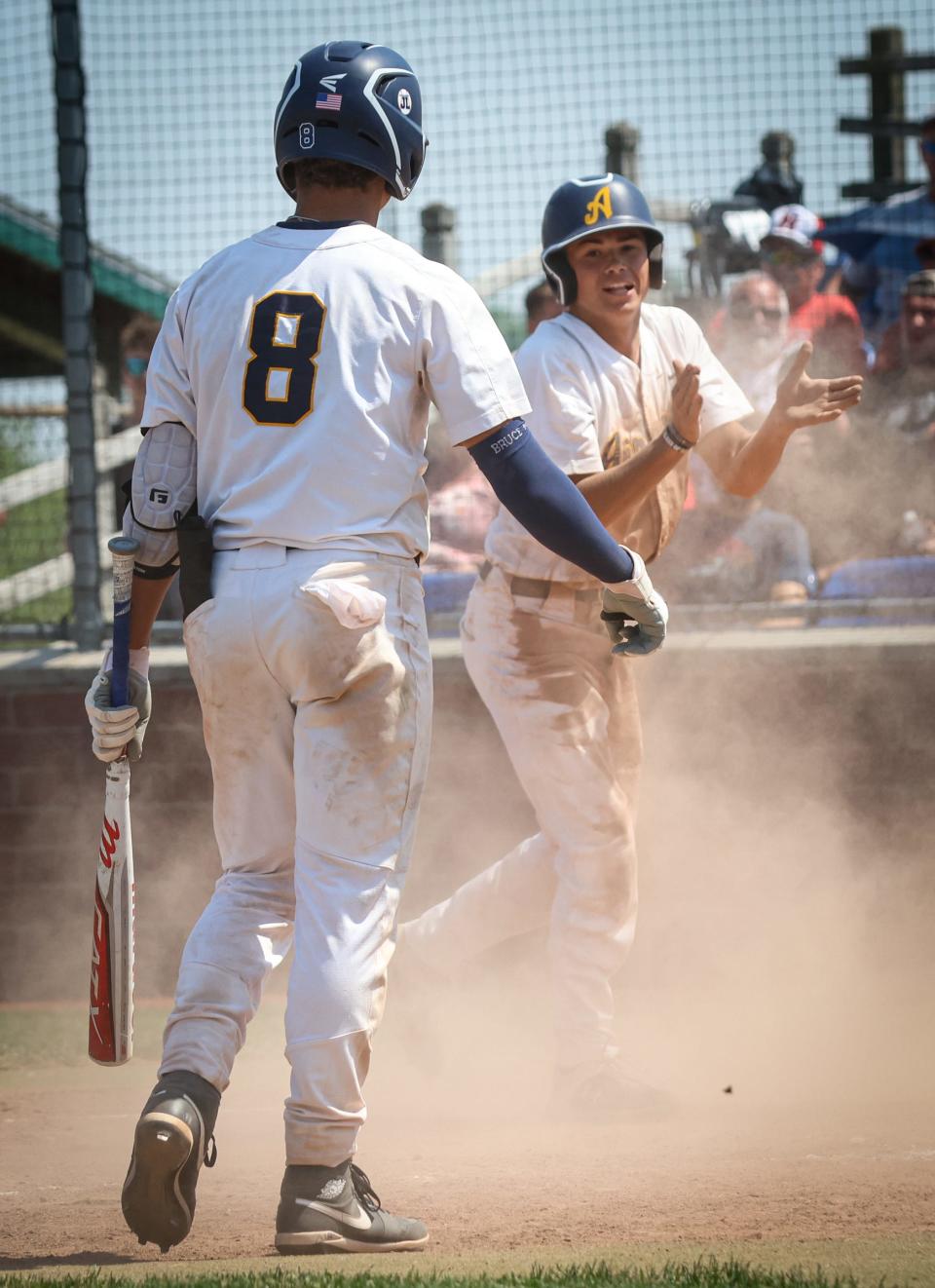 Airport's Jacob VanBuskirk celebrates with teammate Jaden Harper-Lewis after scoring the tying run in the bottom of the third inning against New Boston Huron in the finals of the División 2 District at Airport Saturday. Huron won 4-1 in 10 innings.