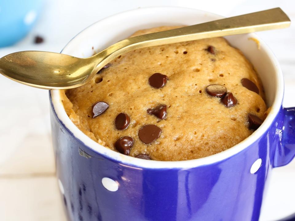 cookie baked in a blue mug with a gold spoon resting on top