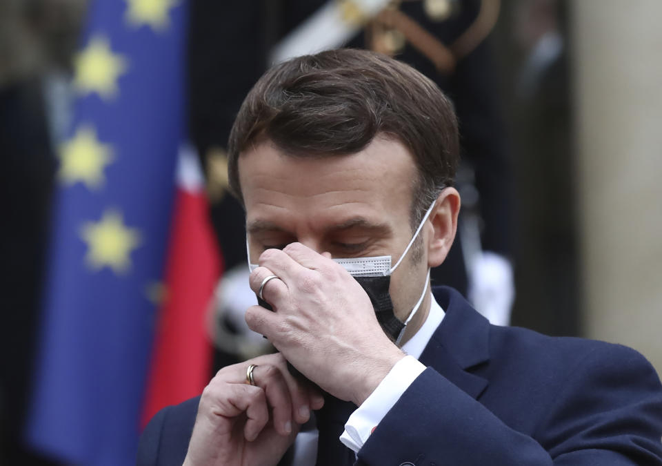 French President Emmanuel Macron takes off his face mask as he welcomes Serbian President Aleksandar Vucic for a working lunch at the Elysee Palace in Paris, Monday, Feb. 1, 2021. Serbian President Aleksandar Vucic is in Paris for bilateral talks with French President Emmanuel Macron. (AP Photo/Michel Euler)