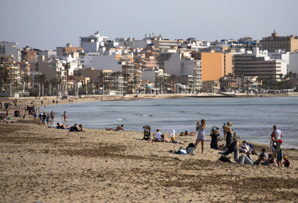 Tourists enjoy the beach at the Spanish Balearic Island of Mallorca, Spain, Monday, March 29, 2021. Efforts in Spain to restart tourism activity is drawing a mixed picture due to a patchwork of national, regional and European rules on travel that is confusing both tourists and their hosts. (AP Photo/Francisco Ubilla)