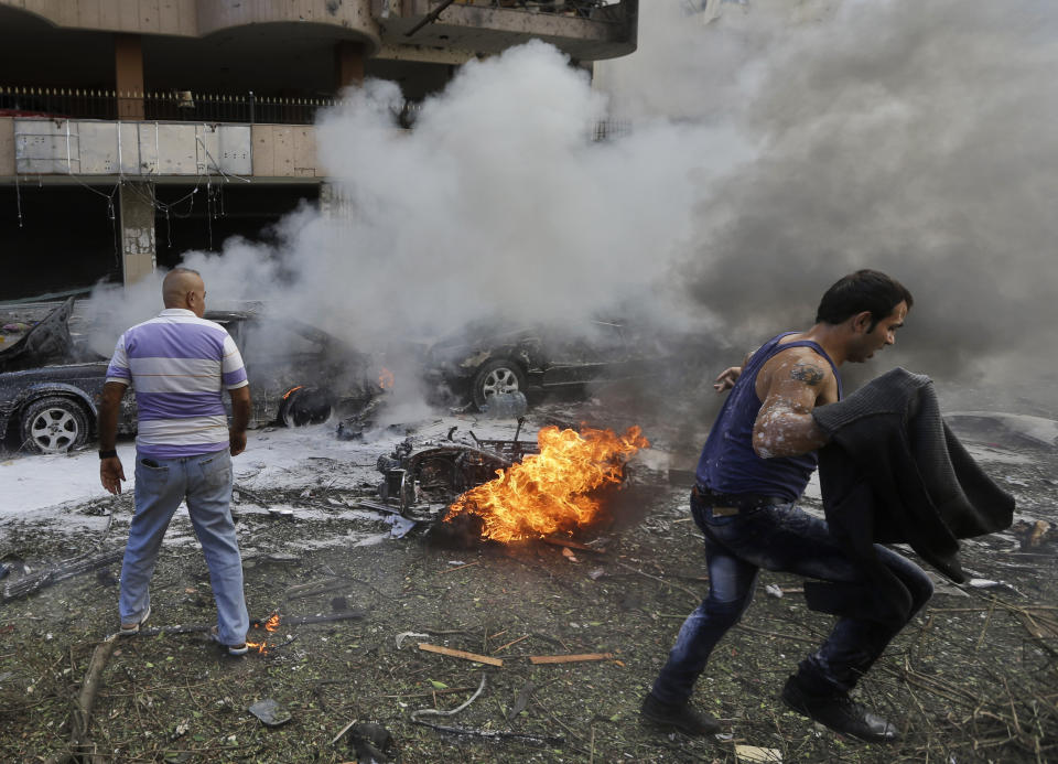 FILE - In this Nov. 19, 2013, file photo, a man runs in front of a burned car at the scene where two deadly explosions struck near the Iranian Embassy in Beirut, Lebanon. Lebanese authorities said Friday, Jan. 3, 2014, that DNA tests have confirmed that a man in government custody, Majid al-Majid, is the alleged leader of the Abdullah Azzam Brigades, an al-Qaida-linked group that has claimed responsibility for the attack on the embassy. (AP Photo/Hussein Malla, File)