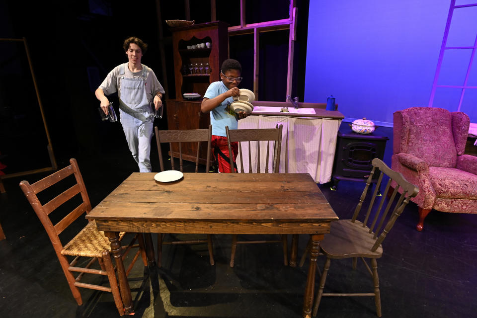 Grayson Hart and cast member Evan Roberts, 11, prepare props on a stage at the Ned R. McWherter West Tennessee Cultural Arts Center in Jackson, Tenn., on Saturday, March 4, 2023. Hart, who directs a youth theater program, was accepted into every college he applied to, but turned them down. He is one of thousands of young adults who graduated high school during the pandemic and are taking career routes other than college. (AP Photo/Mark Zaleski)