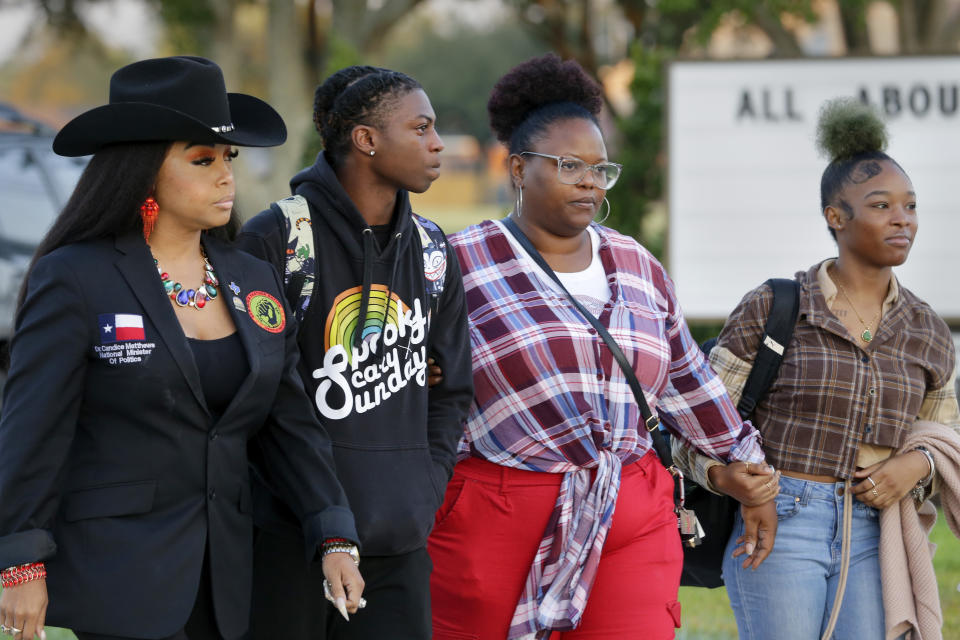 Candice Matthews, left, National minister of politics for the New Black Panther Nation; Darryl George, center left, a 17-year-old junior, and his mother Darresha George, center right, and a unidentified female, right, begin their walk across the street to go into Barbers Hill High School after Darryl served a 5-day in-school suspension for not cutting his hair Monday, Sept. 18, 2023, in Mont Belvieu. (AP Photo/Michael Wyke)