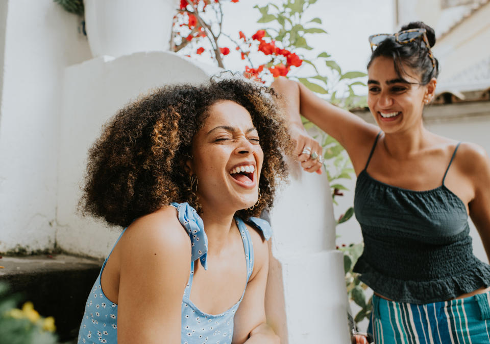 Two women laugh while sitting together in their neighborhood