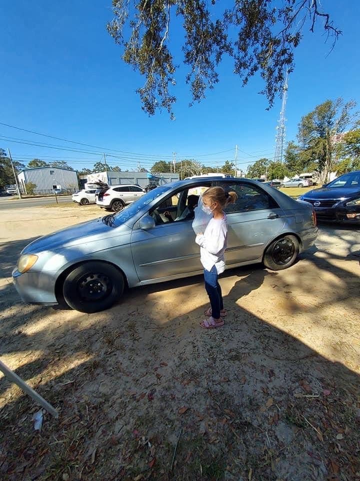 Emily Ley's daughter, Caroline, gives out meals Nov. 20 at the Epps Christian Center in Pensacola.