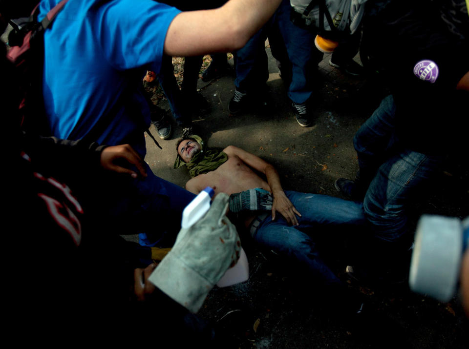 Un manifestante se queja de dolor en el suelo tras choques con agentes antimotines en una protesta antigubernamental en Caracas, Venezuela, el miércoles 12 de marzo de 2014. (AP Photo/Alejandro Cegarra)