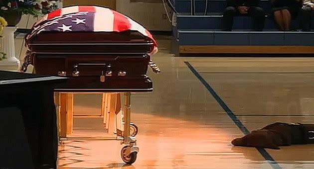 Slain SEAL Tumilson's Labrador Hawkeye lies down next to the casket. Photo: The Daily Mail