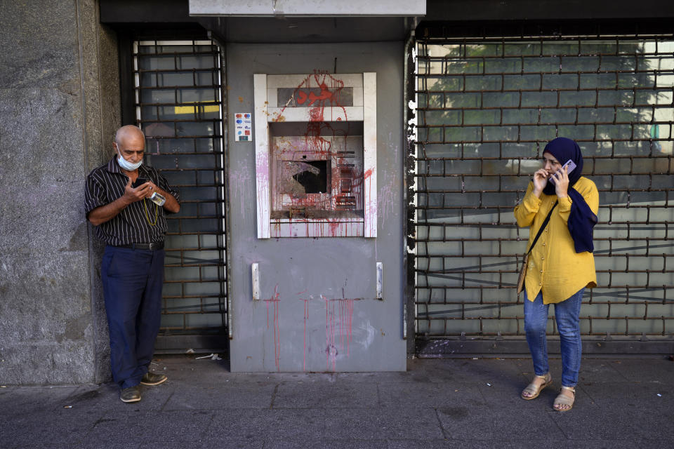 FILE - People waiting outside a Fransabank branch as they stand next to an ATM previously damaged in protests, in Beirut, on Sept. 26, 2022. Angry protesters in Lebanon Thursday Feb. 16, 2023 smashed windows and set tires on fire outside two of the country's biggest banks in the capital city, as the value of the local currency hit a new low and poverty deepens. (AP Photo/Bilal Hussein, File)