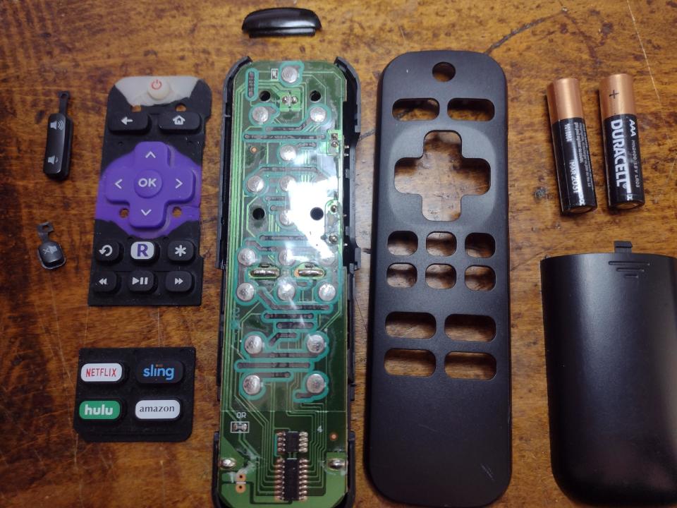 Disassembled remote control with circuit board, rubber keypad, outer casing, and two AA batteries. Streaming service buttons: Netflix, Sling, Hulu, Amazon