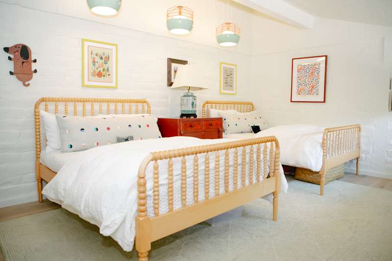 serene white kids room with muted color accents and light wood framed beds