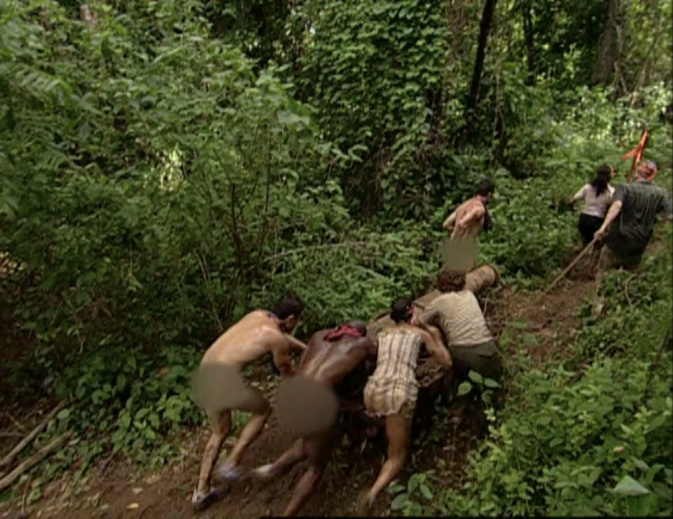 A tribe including three naked men push a cannon through the forest on Survivor: Pearl Islands