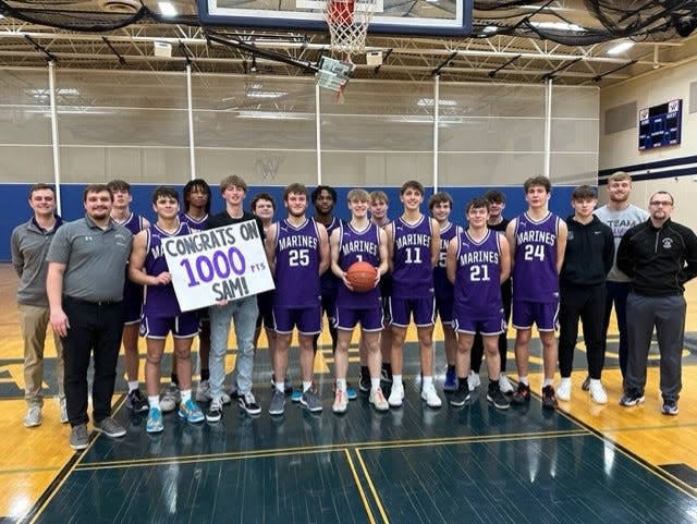 Marinette guard Sam Sommerfeldt (with basketball in hand) recently celebrated scoring 1,000 points.