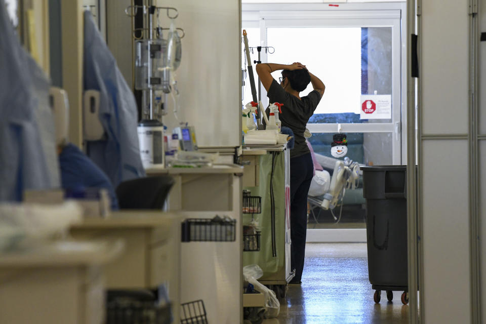 Susan Randolph, a medical worker at East Alabama Medical Center, stretches in the hall of the intensive care unit Thursday, Dec. 10, 2020, in Opelika, Ala. Doctors and nurses caring for the sickest COVID-19 patients are doing what they can to get through the holidays while neighbors and friends indulge in Christmas parades and tree lightings. (AP Photo/Julie Bennett)