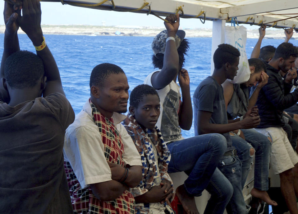 Migrants stand aboard the Open Arms Spanish humanitarian boat as it arrives near Lampedusa coast in the Mediterranean Sea, Thursday, Aug.15, 2019. A Spanish aid boat with 147 rescued migrants aboard is anchored off a southern Italian island as Italy's ministers spar over their fate. (AP Photo/Francisco Gentico)
