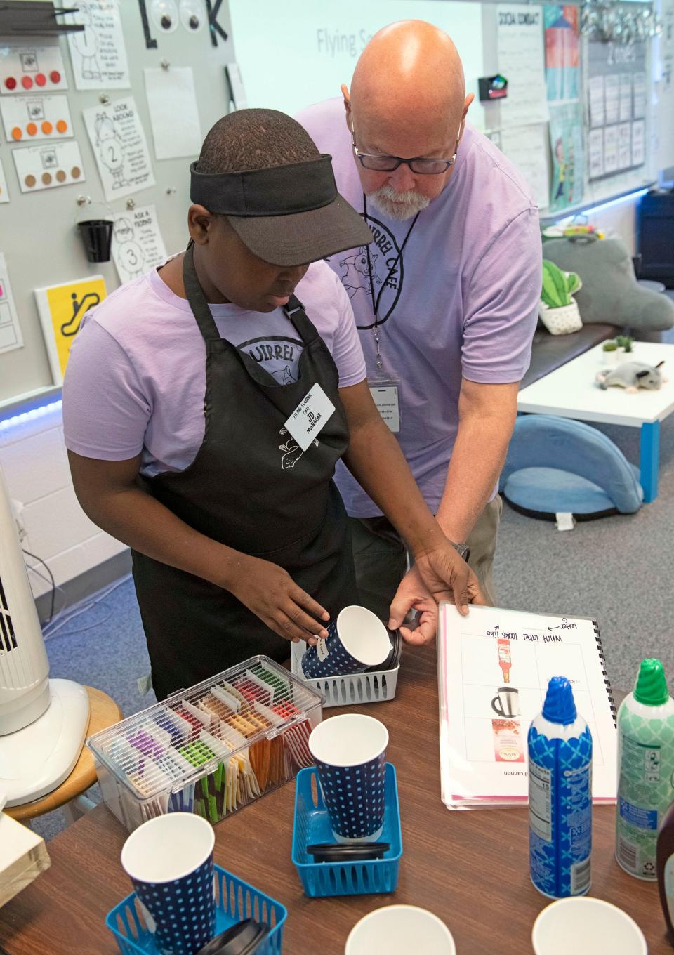 Rhodes Elementary student and Flying Squirrel Cafe manager JD Bryant gets help from Martin Mosio as he works to fulfill a beverage order on Friday, Dec. 1, 2023. The student-run business helps with learning life and social skills by participating in running and operating a business.