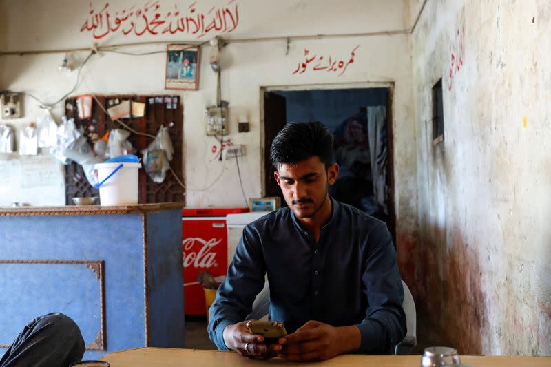 Suleman Asim looks at pictures of his friend Muhammad Ali at a tea stall in Gujrat